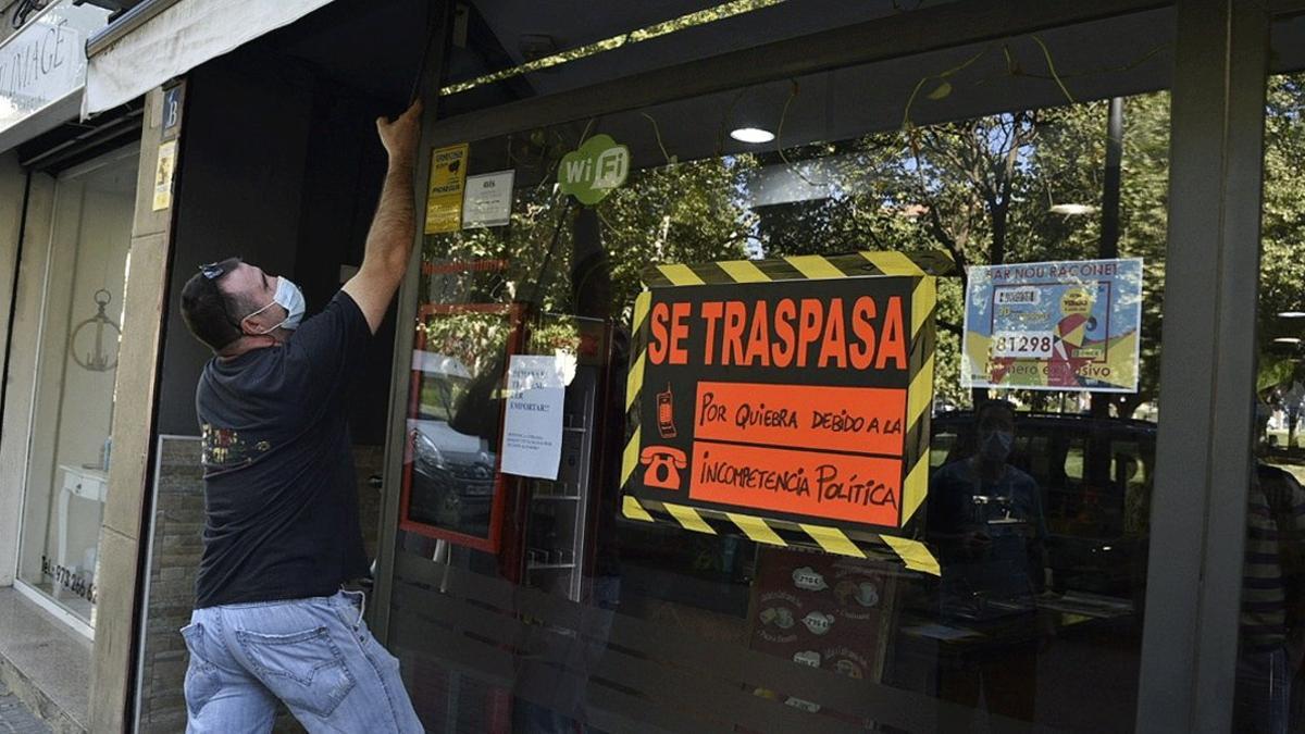 Un hombre baja la persiana de su negocio, en traspaso por la caída de ingresos a raíz del coronavirus, este jueves 16 de julio en València