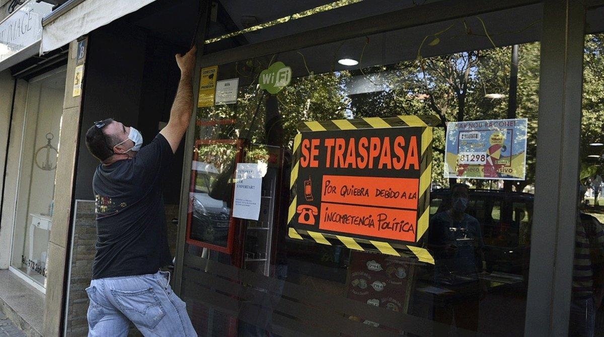 Un hombre baja la persiana de su negocio, en traspaso por la caída de ingresos a raíz del coronavirus, este jueves 16 de julio en València. 
