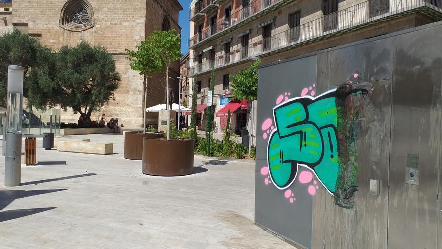 Un grafitero vandaliza el exterior del váter público de la plaza de la Reina