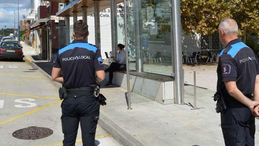 Dos agentes de la Policía, en una parada de autobús mosense. // D.P.