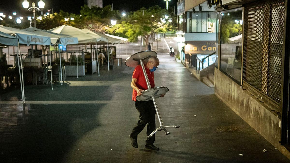 Un camarero recoge las mesas de una terraza anoche de la calle Castillo justo antes del final del toque de queda de las 23:00 horas.
