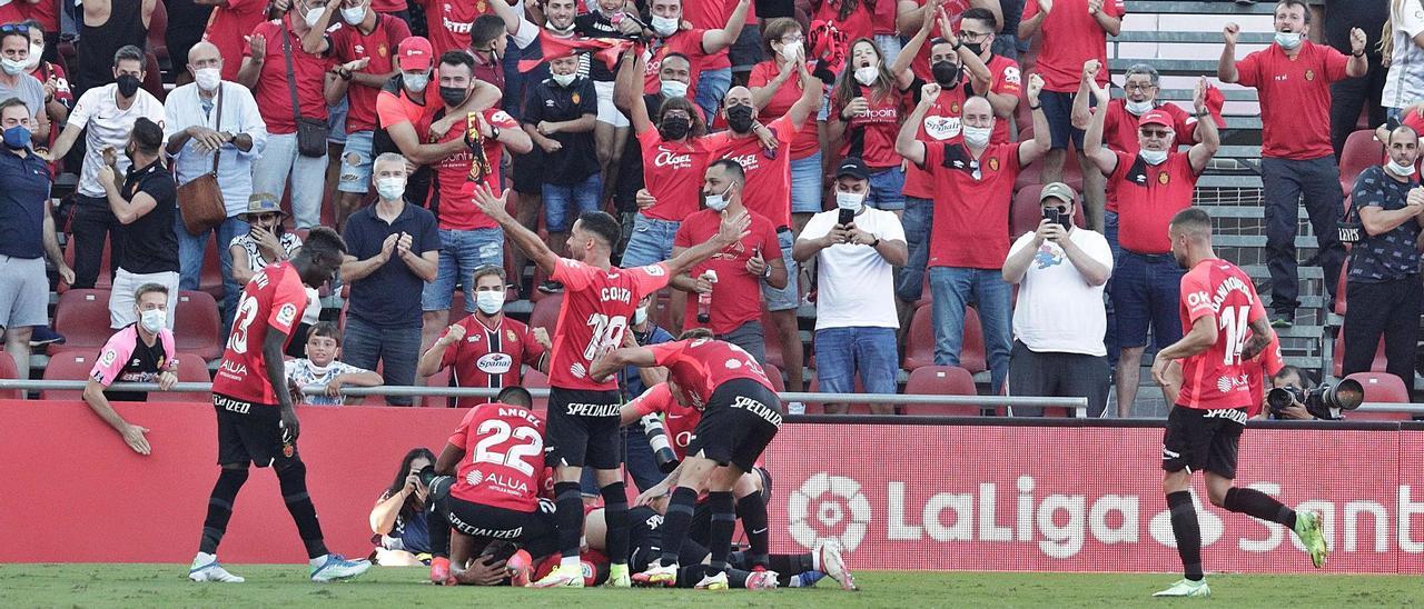 Los jugadores del Mallorca celebran con un abrazo grupal en el suelo el tanto de Ángel ante una grada entregada.  | MANU MIELNIEZUK