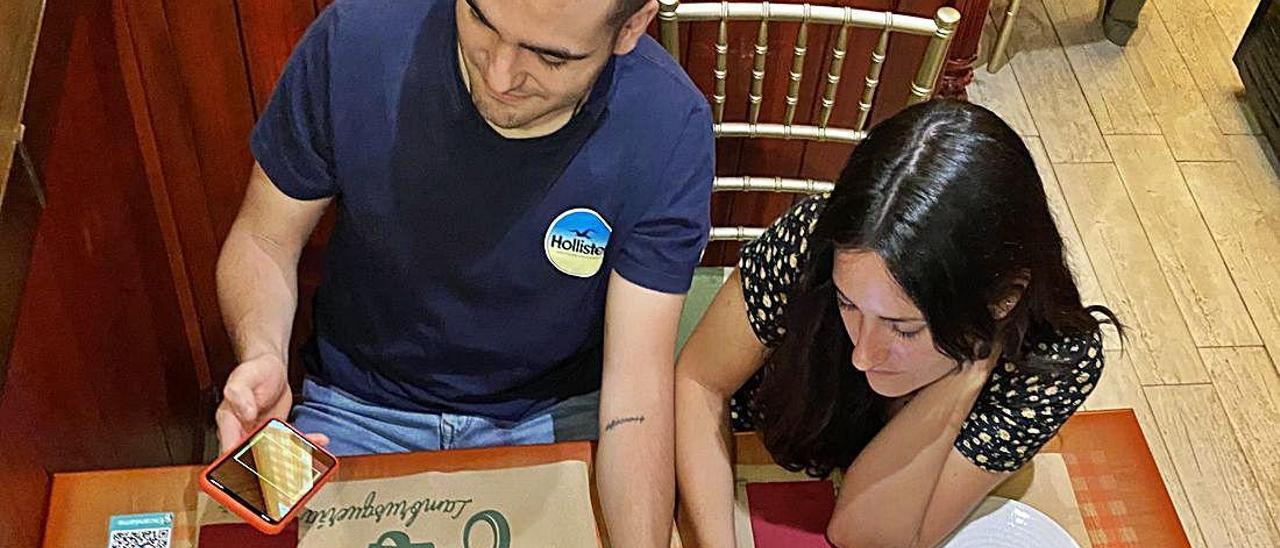 Jóvenes en un bar de Alcoy consultan la aplicación.