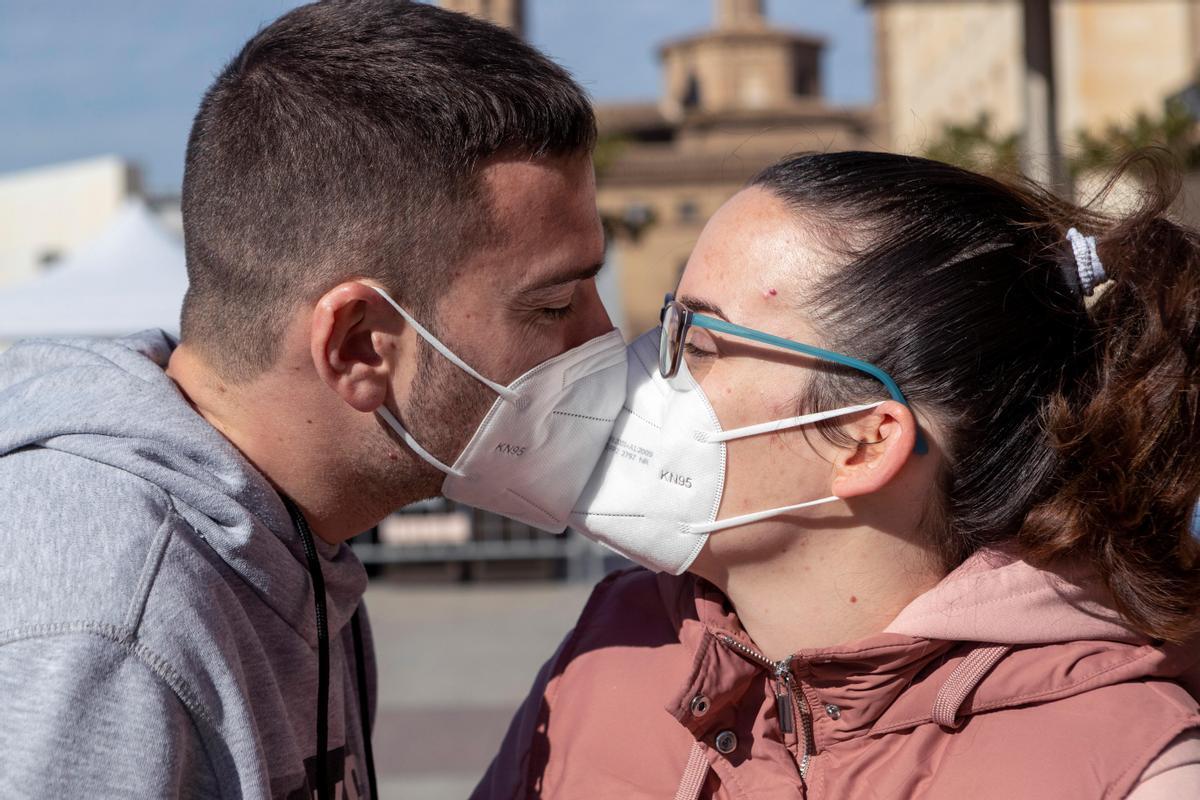 Dos jóvenes se besan, durante la pandemia, pese a sus mascarillas