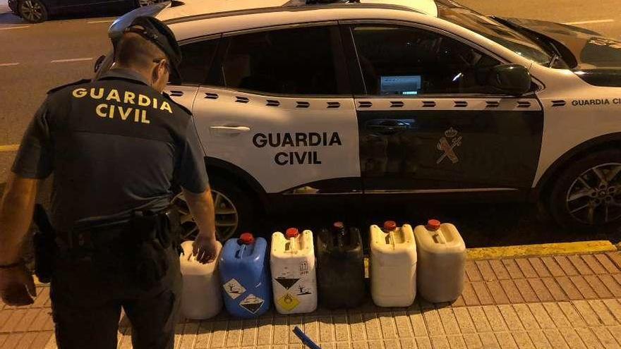 Un agente de la Guardia Civil ante las garrafas incautadas a los detenidos. // Guardia Civil