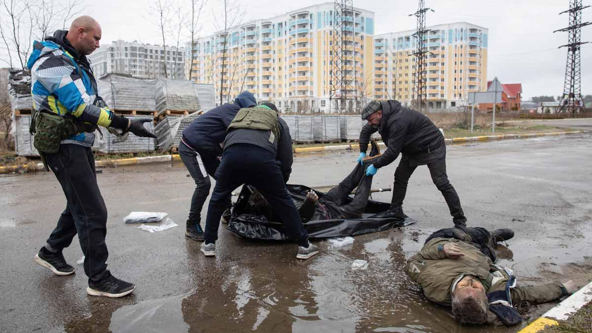Un grupo de hombres retiran cadáveres de civiles ucranianos muertos durante la invasión rusa, en la pequeña ciudad de Bucha