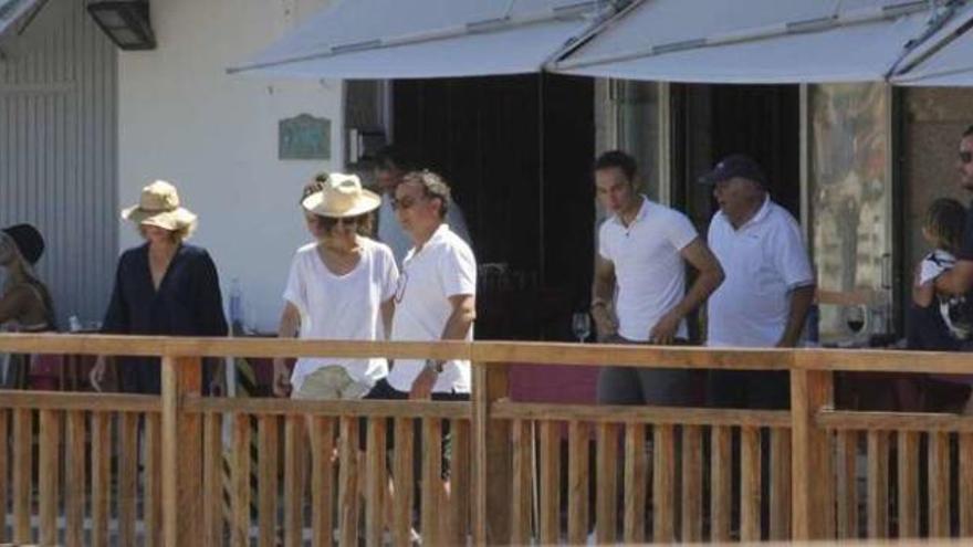 Amancio Ortega sale de la terraza de un restaurante en la playa de O Beluso, precedido por varios familiares y allegados.
