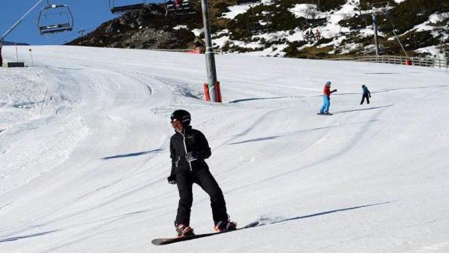 Un joven practicando snowboard, con esquiadores al fondo, en la anterior campaña en Pajares.
