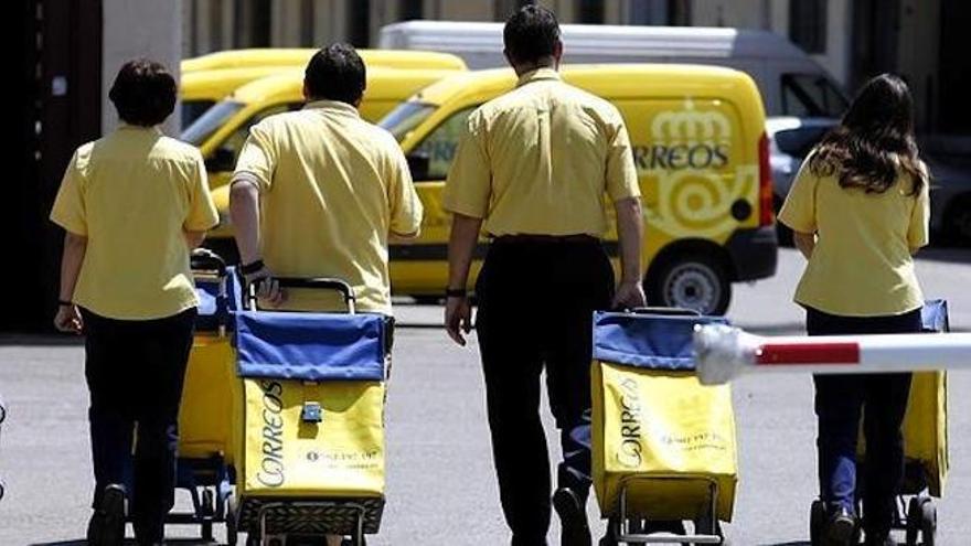 Varios carteros llevan paquetes en Málaga.