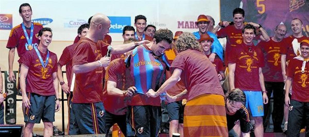 El fitxatge 8 Reina contempla com Puyol i Piqué, darrere de Cesc Fàbregas, posen per sorpresa al centrecampista de l’Arsenal una samarreta del Barça, en la celebració d’ahir.