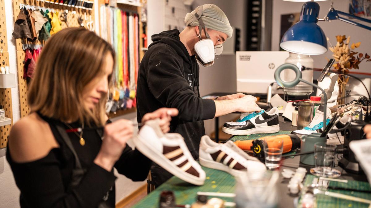 Salvatore pega con cola unas Nike en proceso de resurrección mientras unas Adidas (antes blancas) van tomando color.