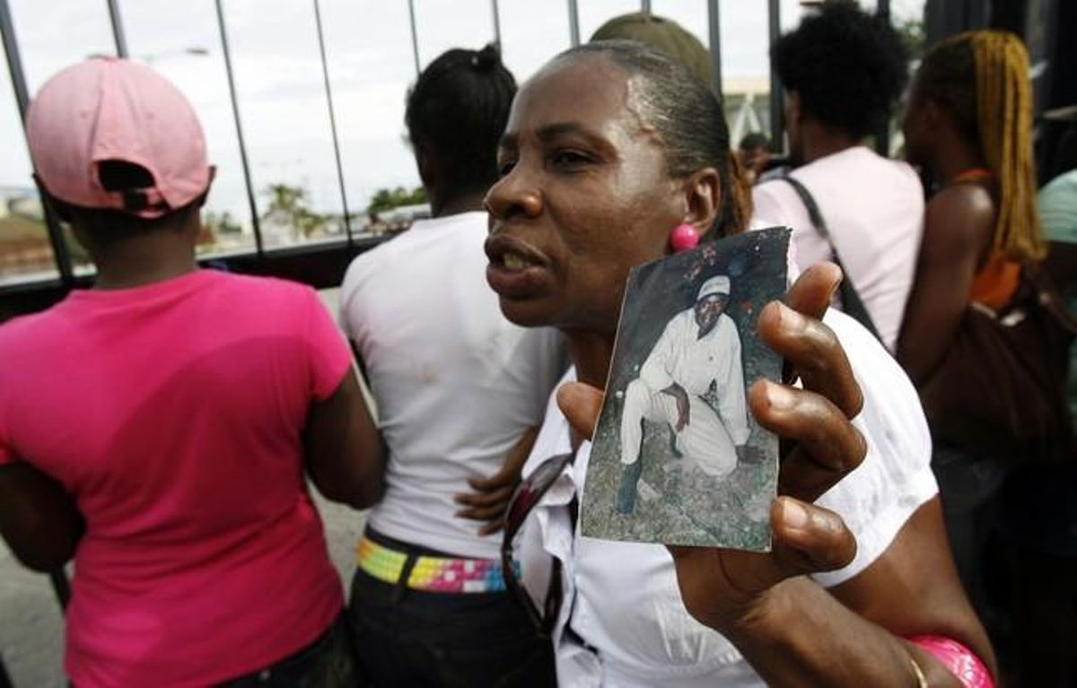 Una dona fa una foto a un membre de la seva família al davant de les portes de l’Estadi Nacional de Jamaica, a Kingston.