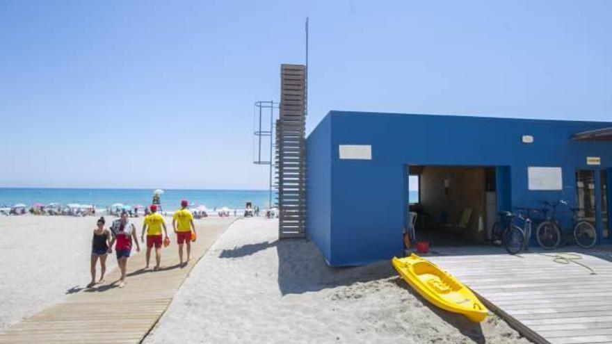 Dos socorristas se dirigen a vigilar la orilla de la playa pasando junto al mástil inutilizado.