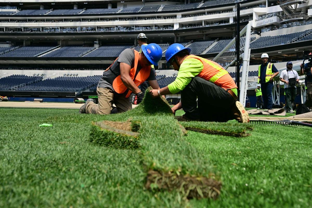 Los trabajadores instalan césped en el campo en el SoFi Stadium en Inglewood, California, antes de su cambio de nombre temporal al Estadio de Los Ángeles para la Copa del Mundo el 13 de mayo de 2026.