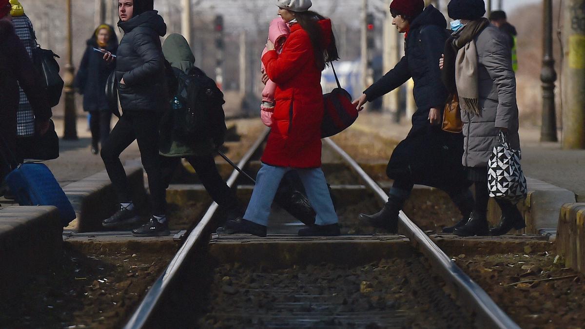 Refugiados ucranianos cruzan las vías del tren en dirección hacia la frontera del país con Rumanía.