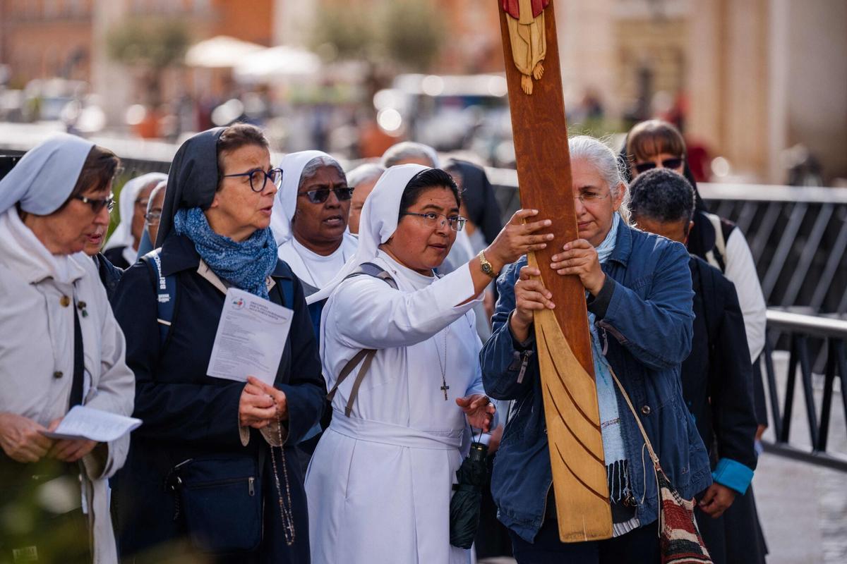 Faithful walk with a cross on Via della Conciliazione street near the Vatican, a day prior to the start of the conclave in Rome on May 6, 2025. (Photo by Dimitar DILKOFF / AFP)