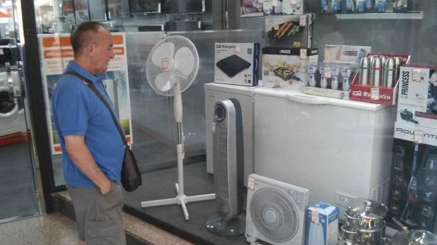 Un hombre observa los ventiladores en el escaparate de una tienda de Benavente, ayer por la mañana.