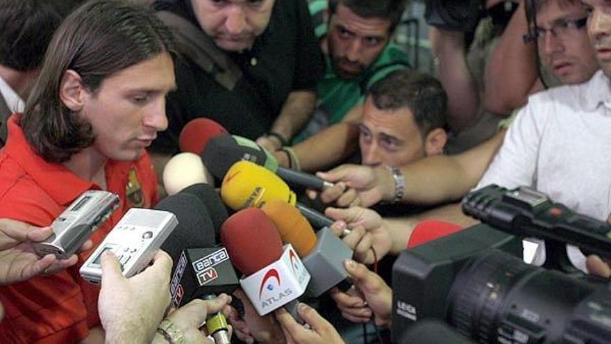 El delantero argentino del F.C. Barcelona, Lionel Messi (i) atiende a los medios de comunicación en el aeropuerto de Barcelona antes de partir hacia Florencia donde esta noche el club azulgrana disputa un partido amistoso ante la Fiorentina.