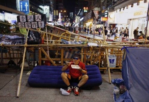 A pro-democracy protester eats his meal in front of a barricade blocking a main road in Mongkok