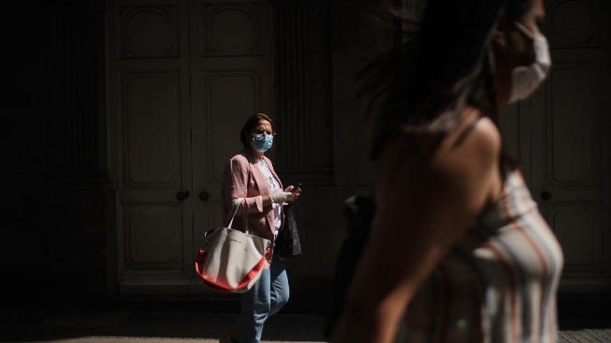 Una mujer pasea por una calle de Santa Cruz portando su móvil y garantizado las medidas de seguridad.