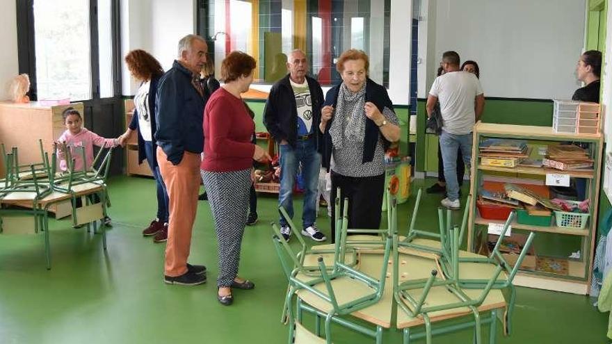 Unas personas observan un aula, ayer, durante la jornada de apertura de puertas del colegio Igrexa. // FdV