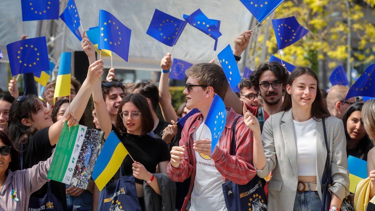 Jóvenes con banderas de la UE y de Ucrania durante un acto en Bruselas, este lunes.