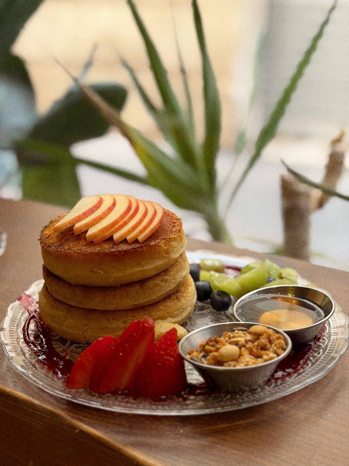 Pancakes mit Früchten, Bananensirup, Müsli und Erdbeermarmelade.