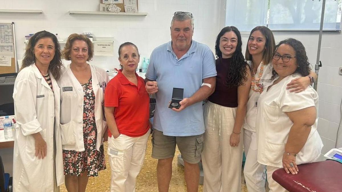 Joaquín Serra, acompañado por su hija María Isabel y por el equipo sanitario, muestra la placa recibida en reconocimiento a sus 91 donaciones de sangre.