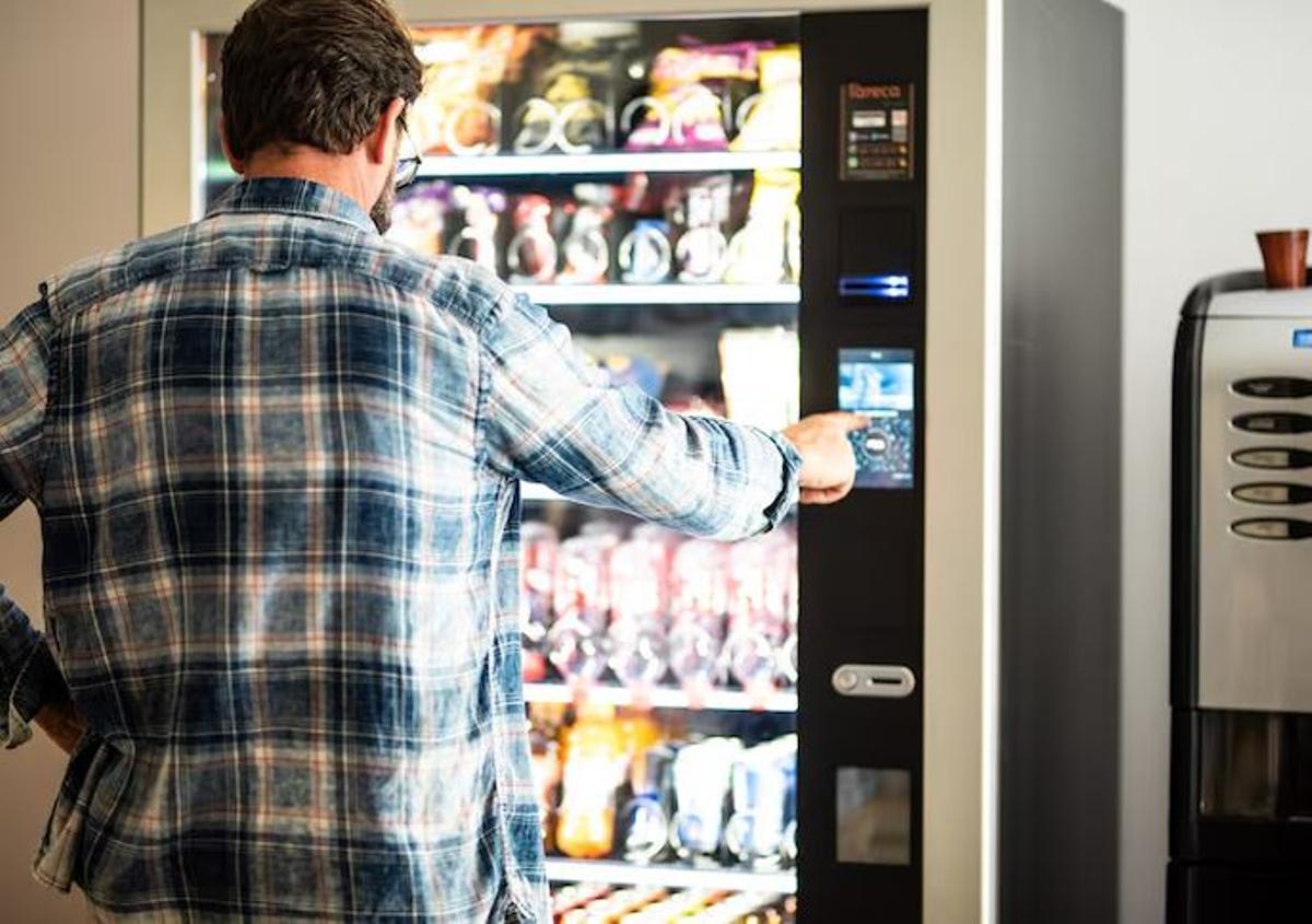 Un hombre compra un producto en la máquina expendedora de su oficina.