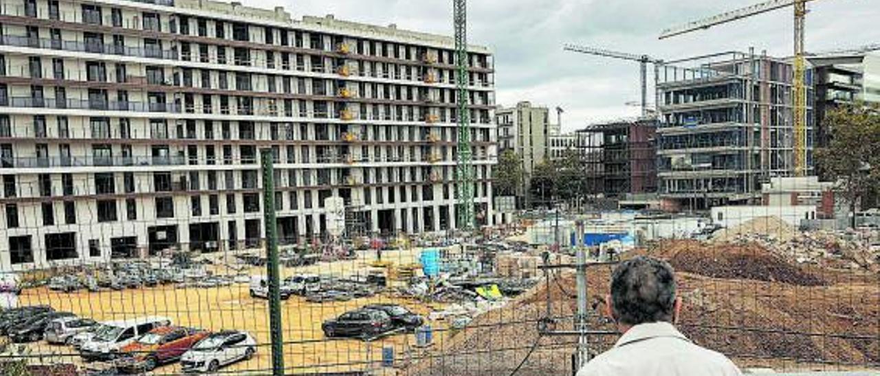 Un hombre mira unas viviendas en construcción.