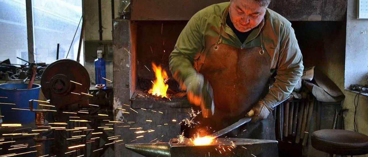 César Castaño trabajando en la fragua de su taller, en Navelgas (Tineo).