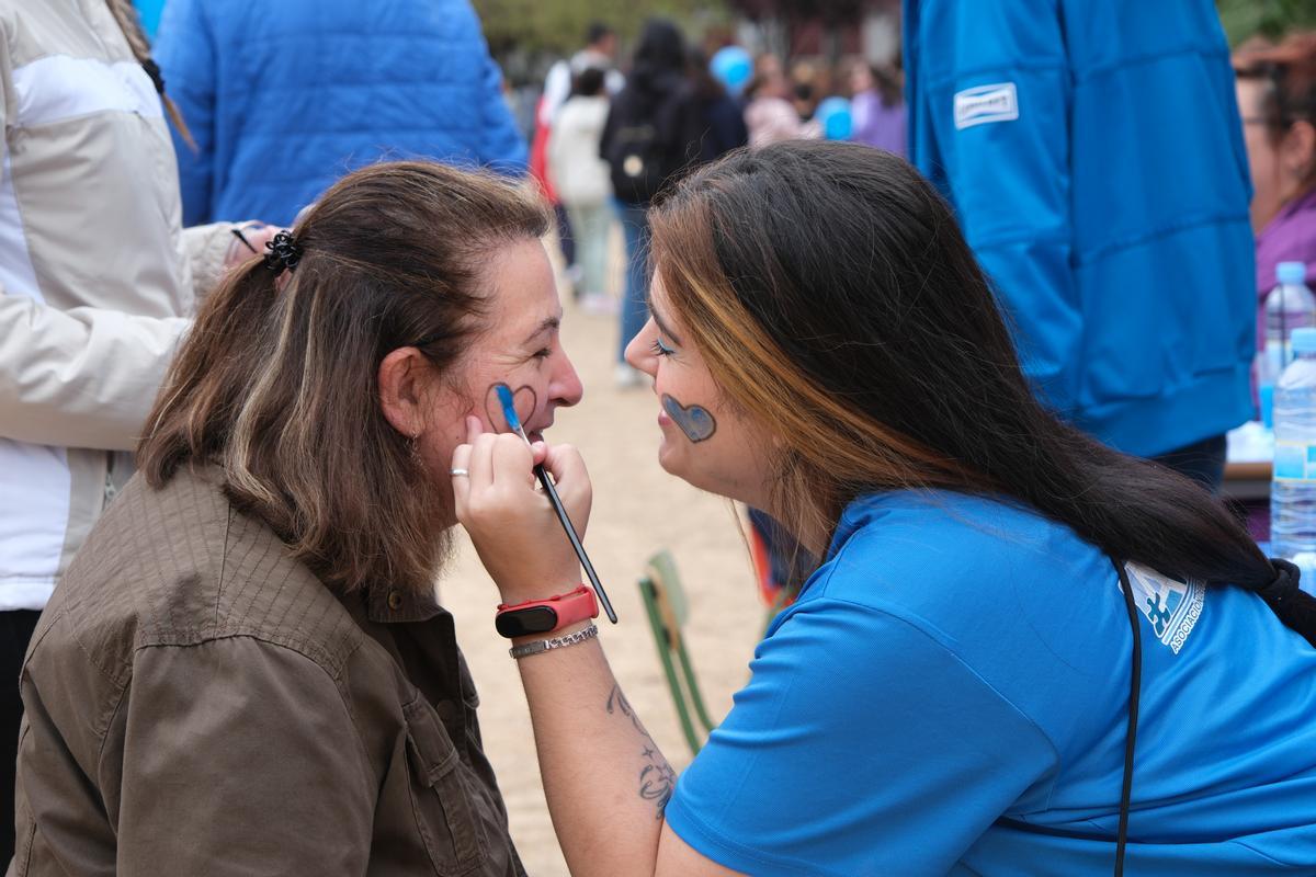 Una chica se pinta un corazón azul en la cara.