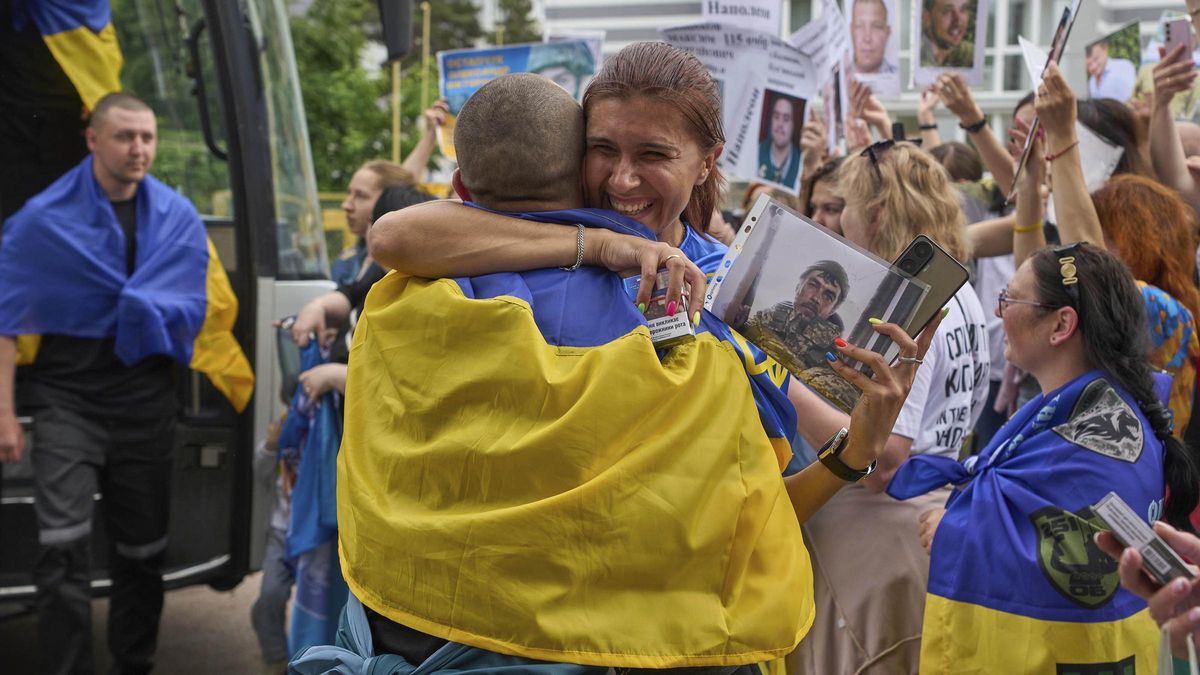 Una mujer abraza a un soldado que regresó del cautiverio ruso mientras la gente muestra fotos de soldados desaparecidos durante un intercambio de prisioneros entre Rusia y Ucrania, en la región de Chernyhiv, Ucrania.