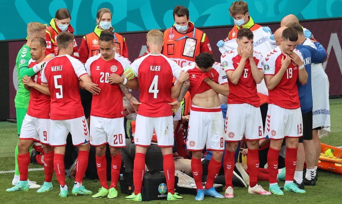 TOPSHOT - Denmark's players gather as paramedics attend to midfielder Christian Eriksen (not seen) during the UEFA EURO 2020 Group B football match between Denmark and Finland at the Parken Stadium in Copenhagen on June 12, 2021. (Photo by WOLFGANG RATTAY / various sources / AFP)