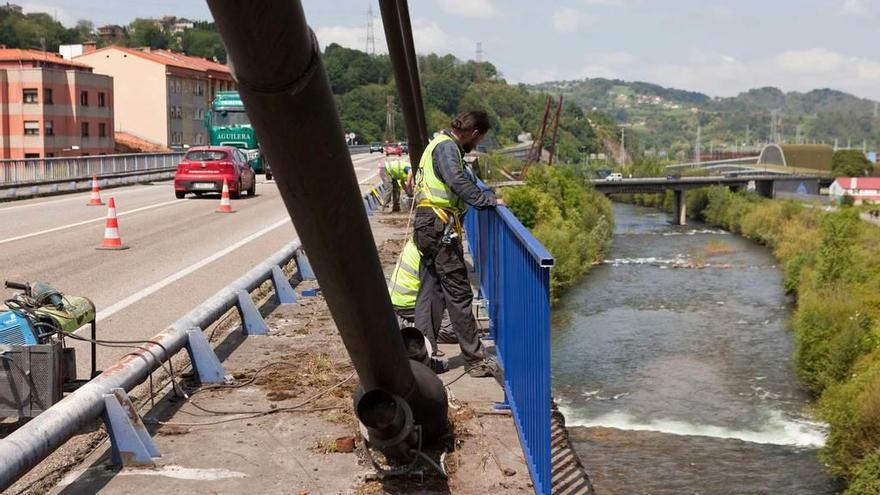 Un operario retira un tramo de barandilla del puente de Sama.