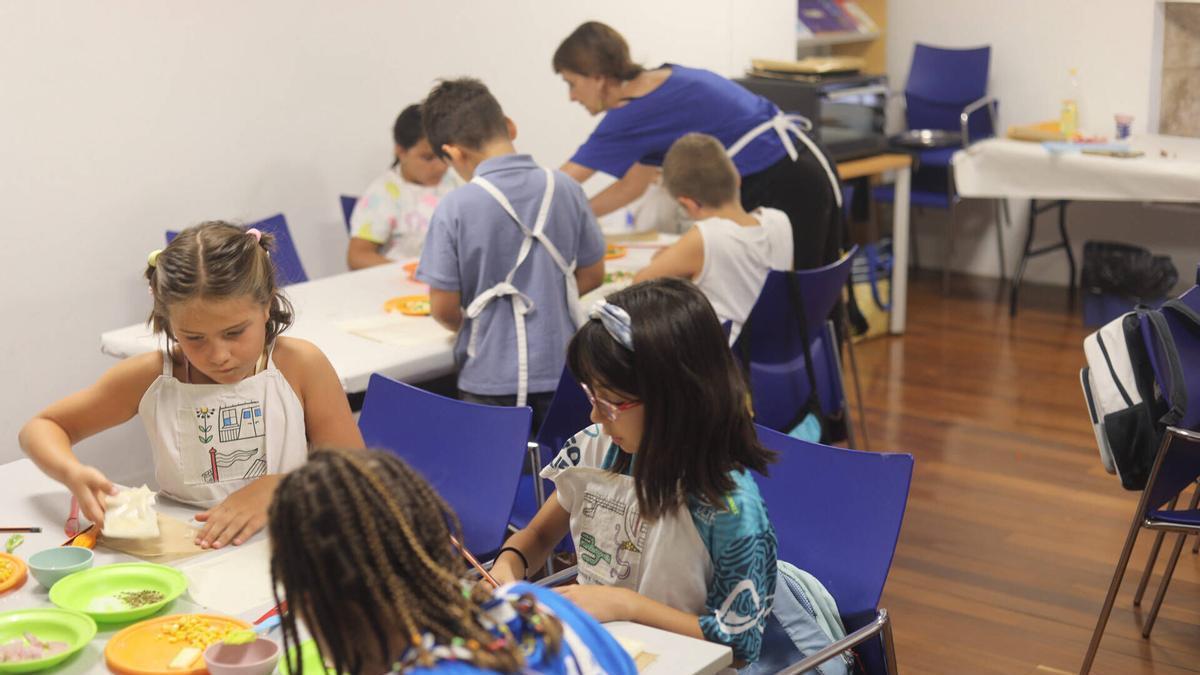 Los niños y niñas participantes en el taller cortan los ingredientes para elaborar rollitos de hortalizas chinos en una de las salas del Palacio de la Alhóndiga de Zamora.