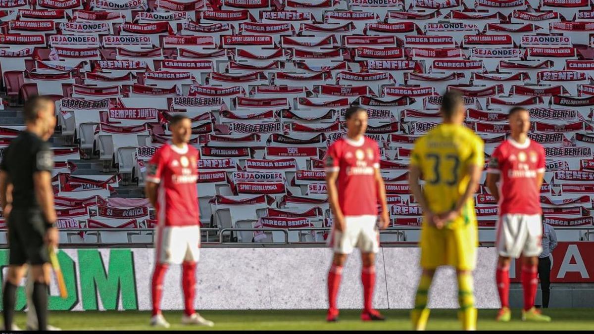 Jugadores del Benfica guardan un minuto de silencio por los víctimas del coronavirus antes de empatar ante el Tondela.