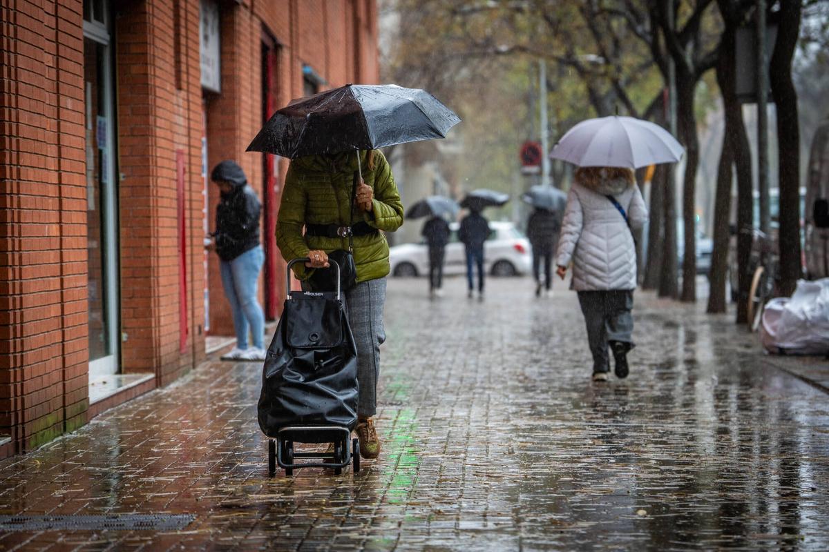 Gente con paraguas bajo la lluvia en Barcelona.