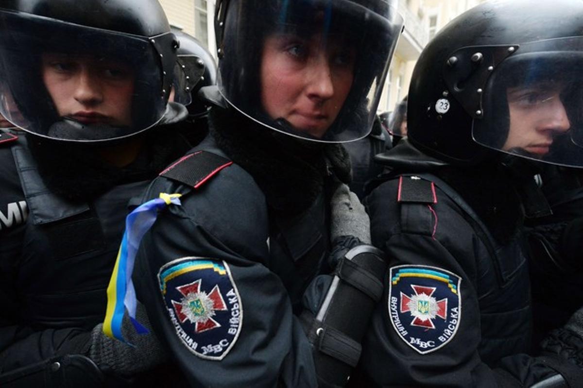 Miembros de la policía se protegen del enfrentamiento contra los manifestantes.