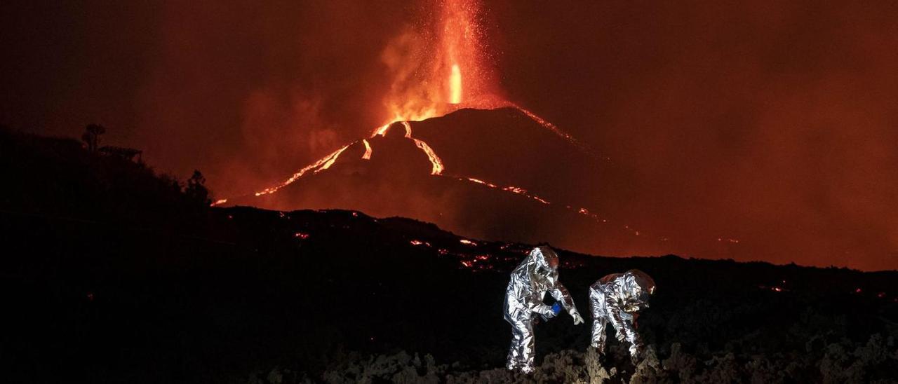 El sargento Salazar y el cabo Heredia de la UME recogen muestras de lava para el IGME vestidos con un traje especial con escudo térmico, andando sobre lavas a más de 400 grados. | | ARTURO RODRÍGUEZ