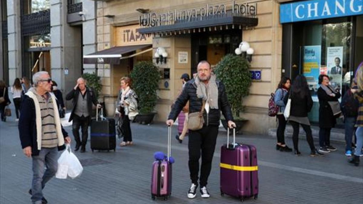MENOS TURISTAS Unos huéspedes salen con sus maletas de un hotel.
