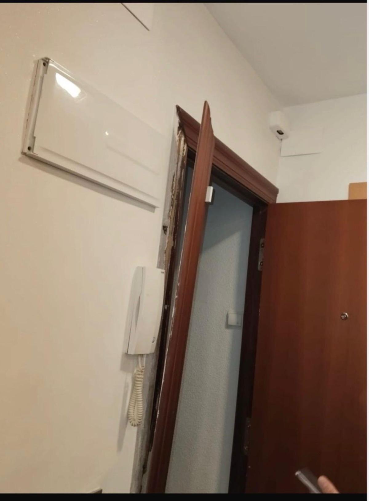 Estado en el que quedó la puerta de acceso a la vivienda tras la entrada por error de la Policía Nacional