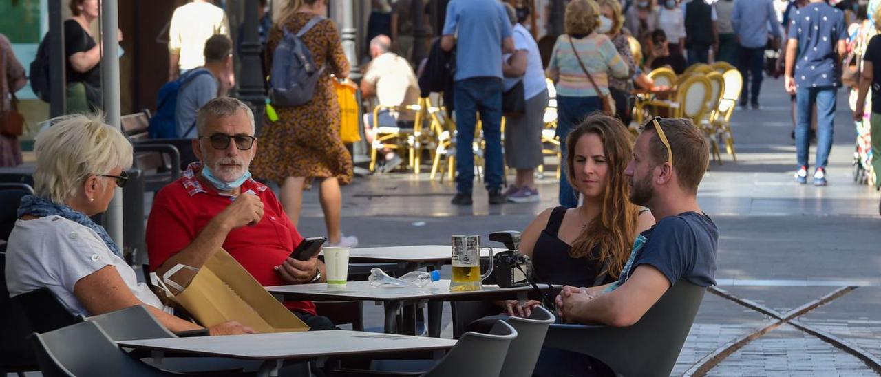 Turistas toman una cerveza en una terraza de Triana tras ir de compras este fin de semana.