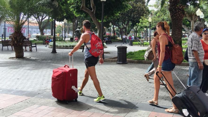 Dos turistas caminan con sus maletas por el parque Santa Catalina.