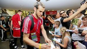 Bale firma autógrafos a unos aficionados galeses.