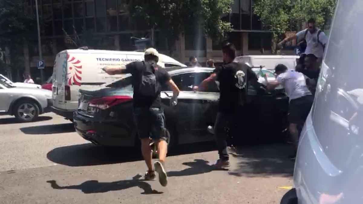 Manifestantes durante la huelga de taxis en Barcelona atacan un coche de Cabify