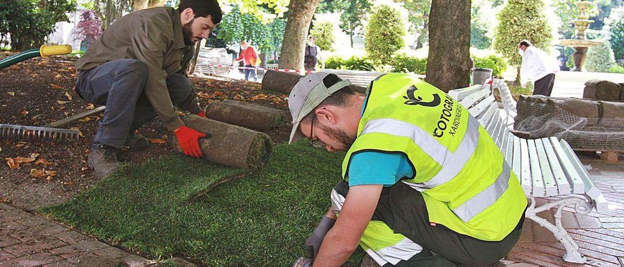 Operarios, colocando los rollos de tepes de césped, ayer, en San Lázaro.