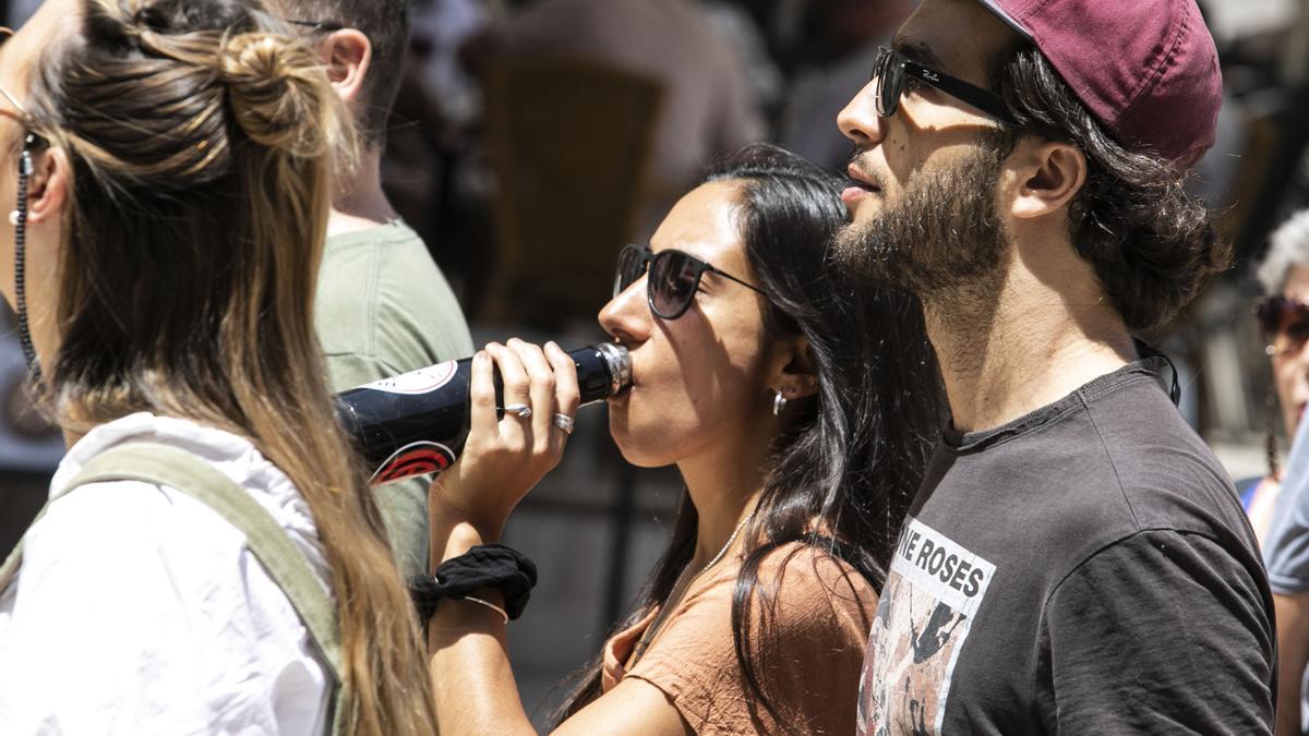 Un grupo de personas pasea por la calle a pleno sol.