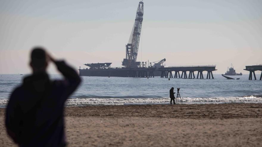 Vecinos del Port de Sagunt observan desde la playa la retirada de las tolvas del Pantalán