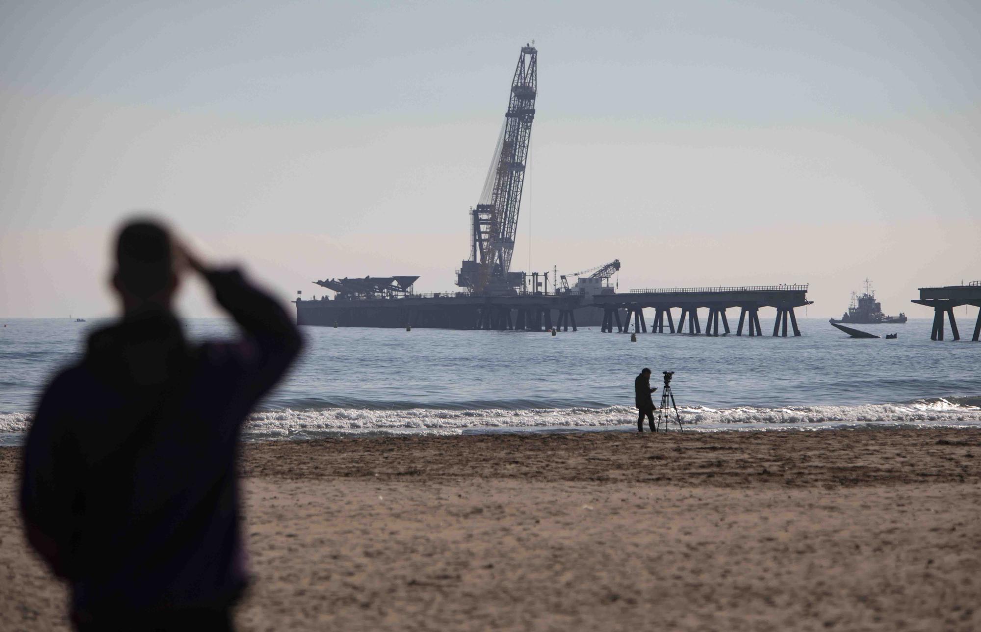 Vecinos del Port de Sagunt observan desde la playa la retirada de las tolvas del Pantalán